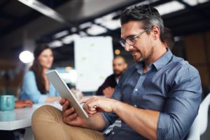 Man in office looking at looking at tablet reading the article Why Agent Advantage Life Insurance Leads Outperform All Others