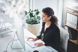 Business Woman Sitting at Desk Looking at Desktop Computer