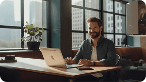 Male Life Insurance Broker at desk with laptop smiling after Mastering Up-Sales and Cross-Sales for IULs