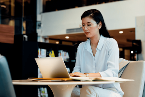 Female Life Insurance Agent Sitting at public table looking at open laptop